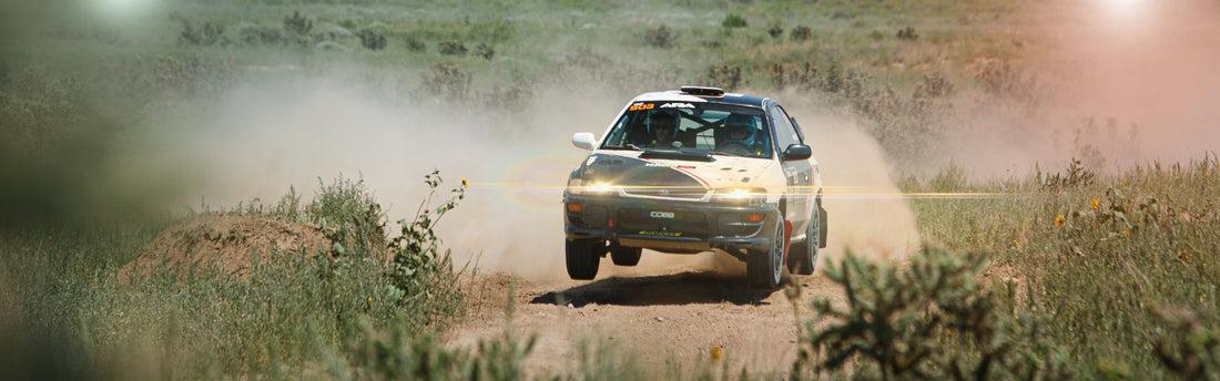 A rally car catching air as it turns a corner.