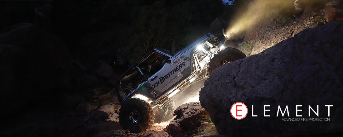 An off-road vehicle climbs a mountain of rocks in dark