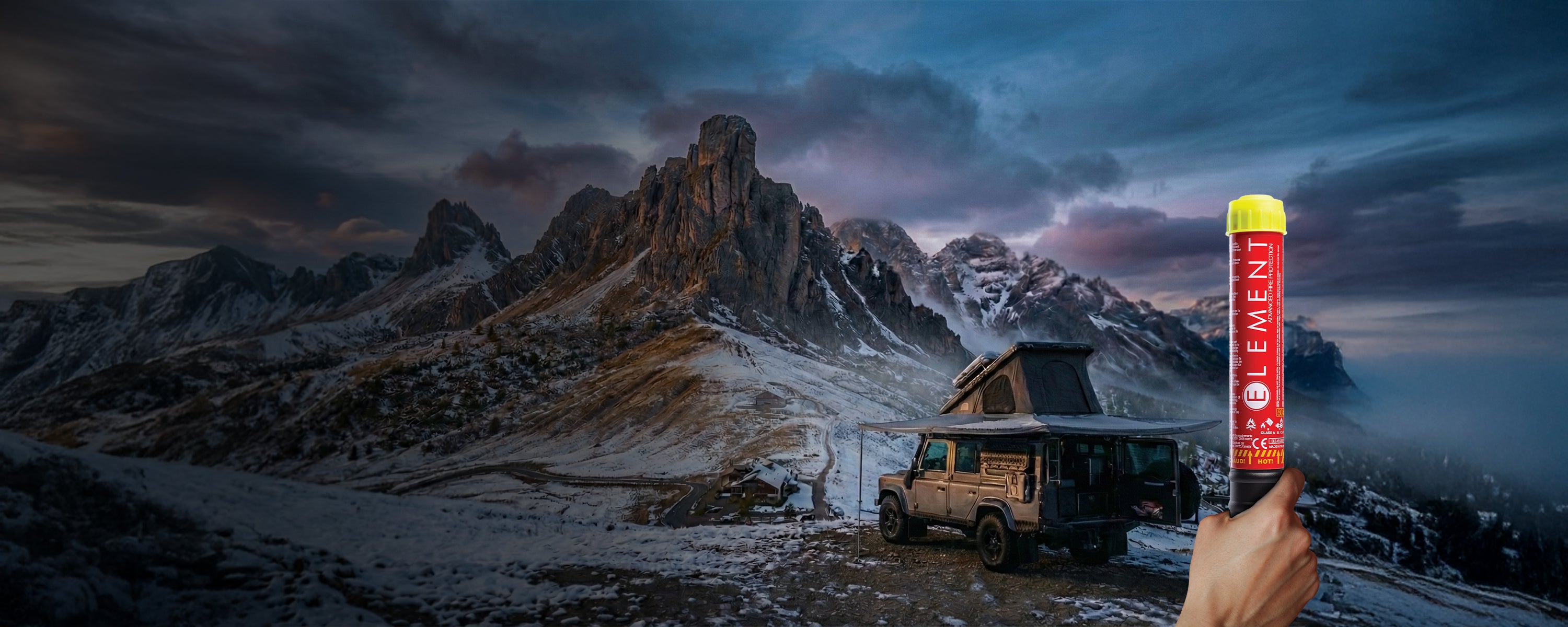 Element Fire Extinguisher held in front of a fully equipped overlanding vehicle parked in front of a scenic winter mountain landscape.